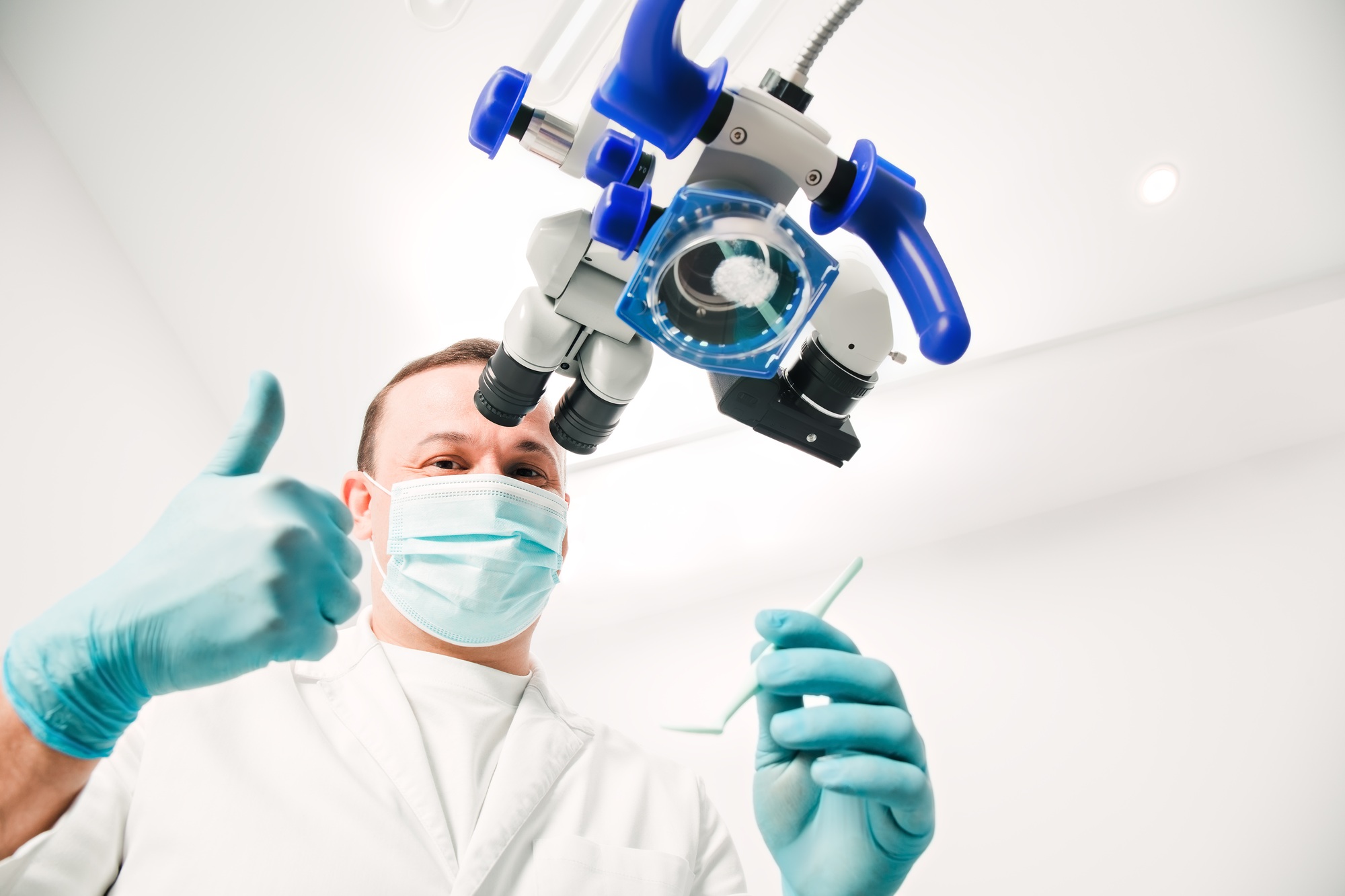 Male dentist in dentist office. Dental doctor wearing lab gown, gloves and medical mask