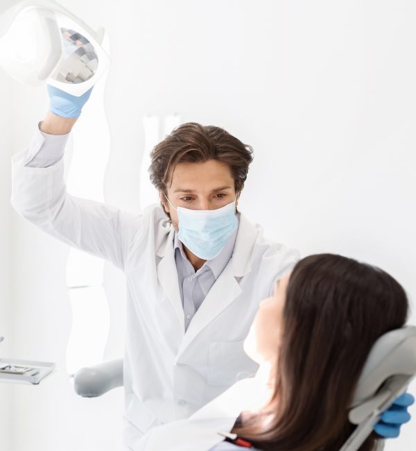 Attentive dentist listening to female patient in cabinet