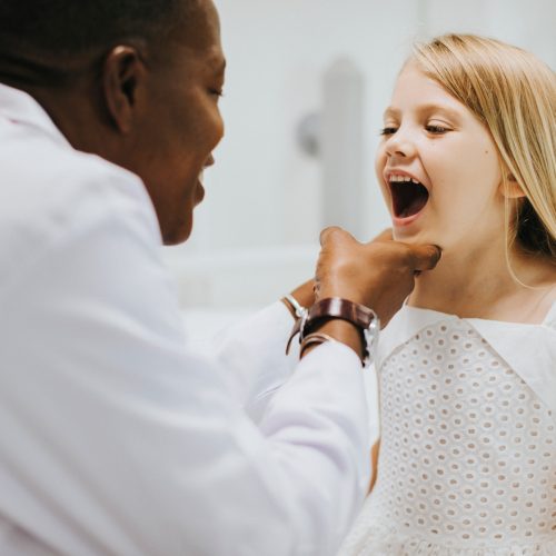 Young girl showing a dentist her teeth